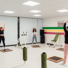 Three women engage in a workout session in a brightly lit, modern fitness studio in Yalova, Türkiye.